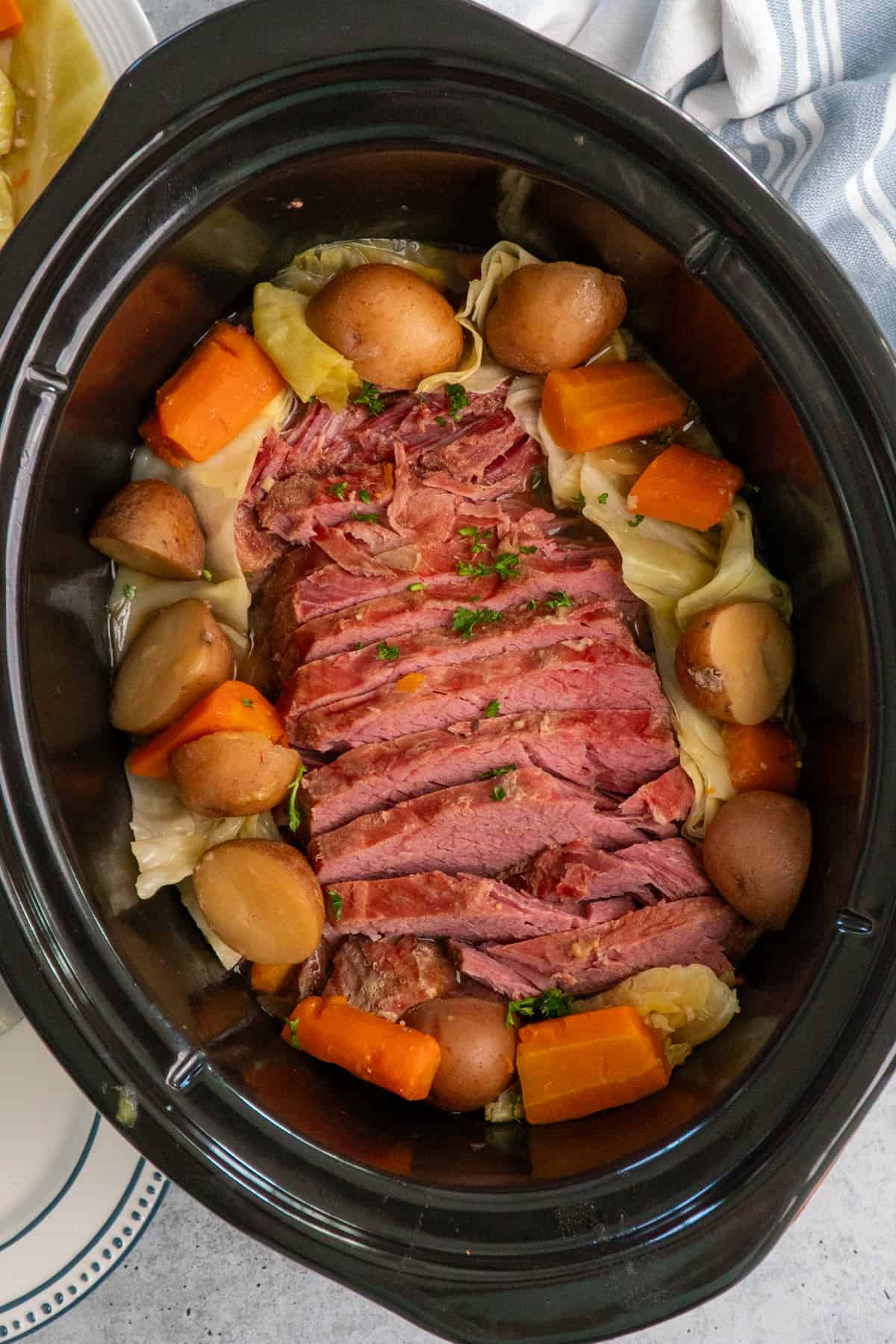Overhead look at corned beef and cabbage in a slow cooker.