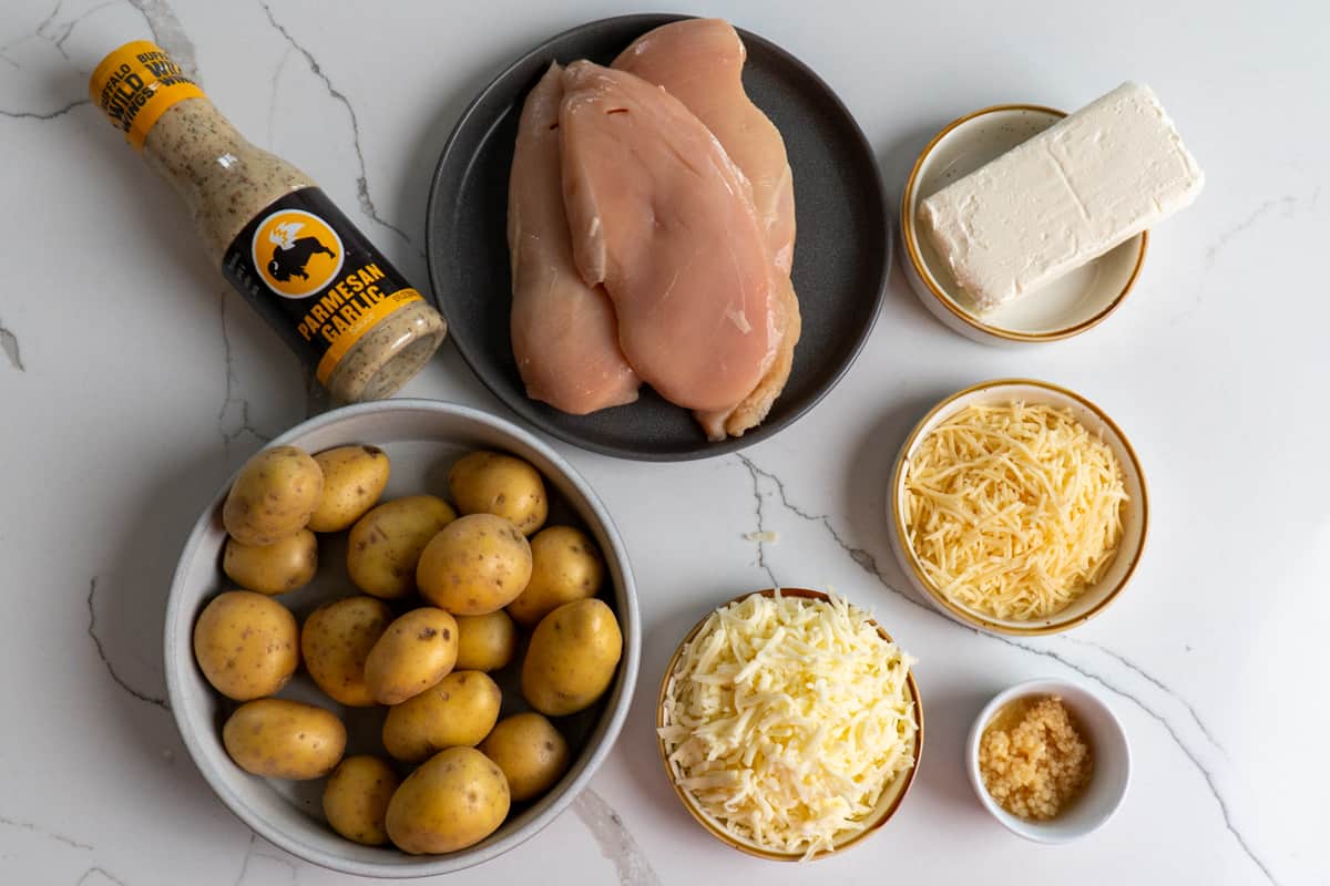 All the ingredients to make this recipe: Baby potatoes, parmesan sauce, chicken breasts, parmesan cheese, mozzarella cheese, garlic and cream cheese.