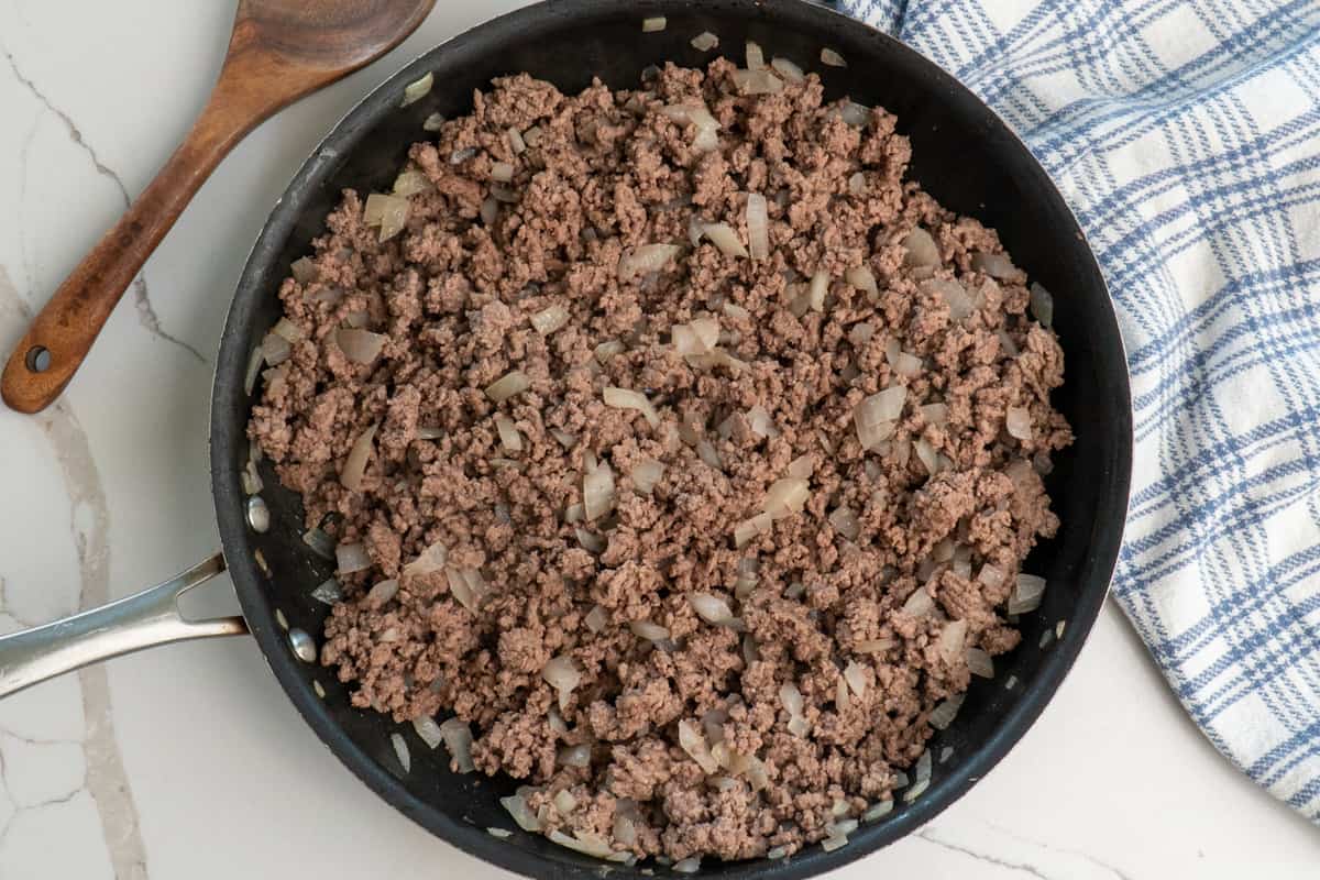 Cooked ground beef and onions in a skillet.