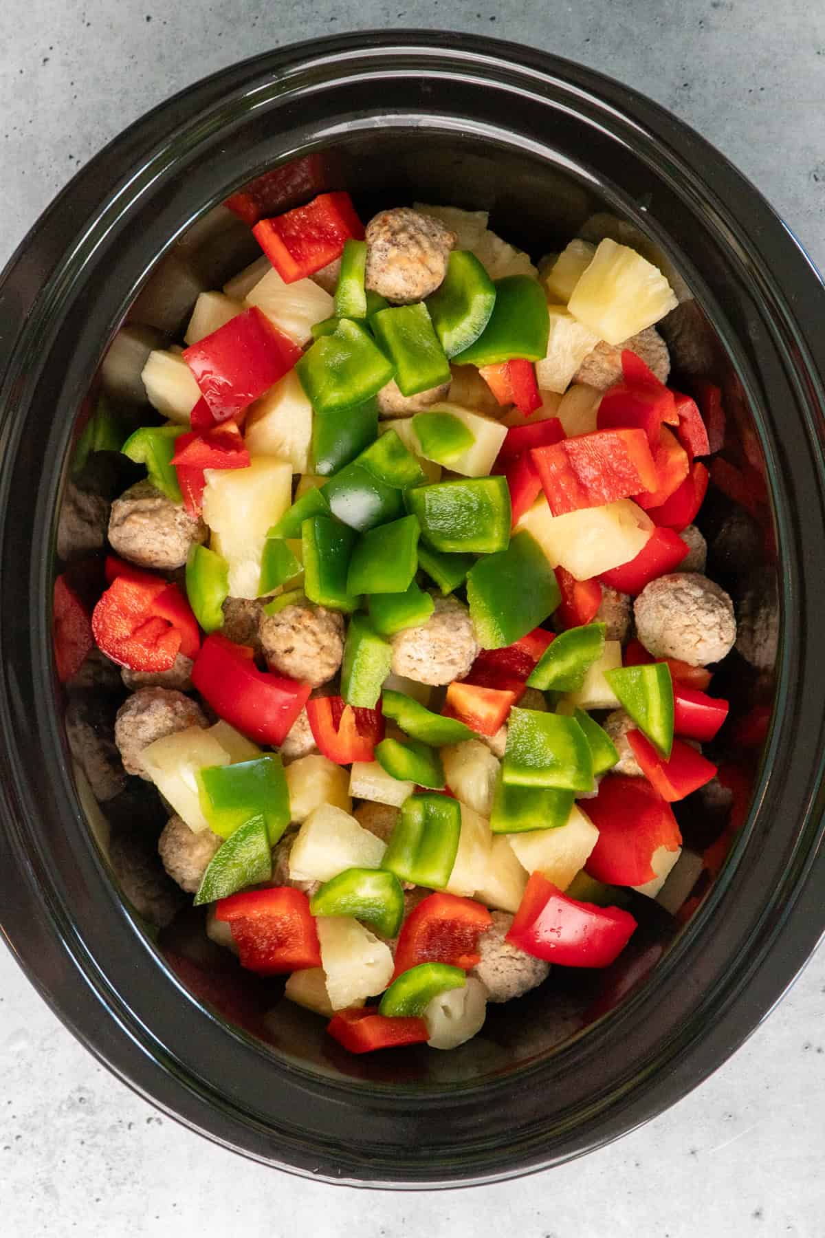 Overhead look at meatballs pineapple, bell peppers in a bowl.