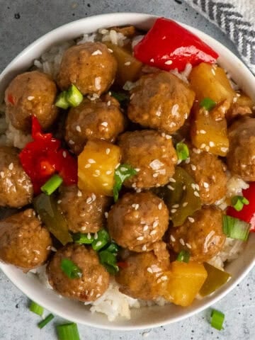 Overhead look at slow cooker teriyaki meatballs over a bowl of rice.