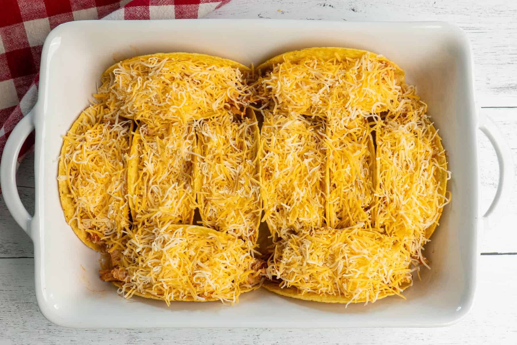 Tacos topped with shredded cheese.
