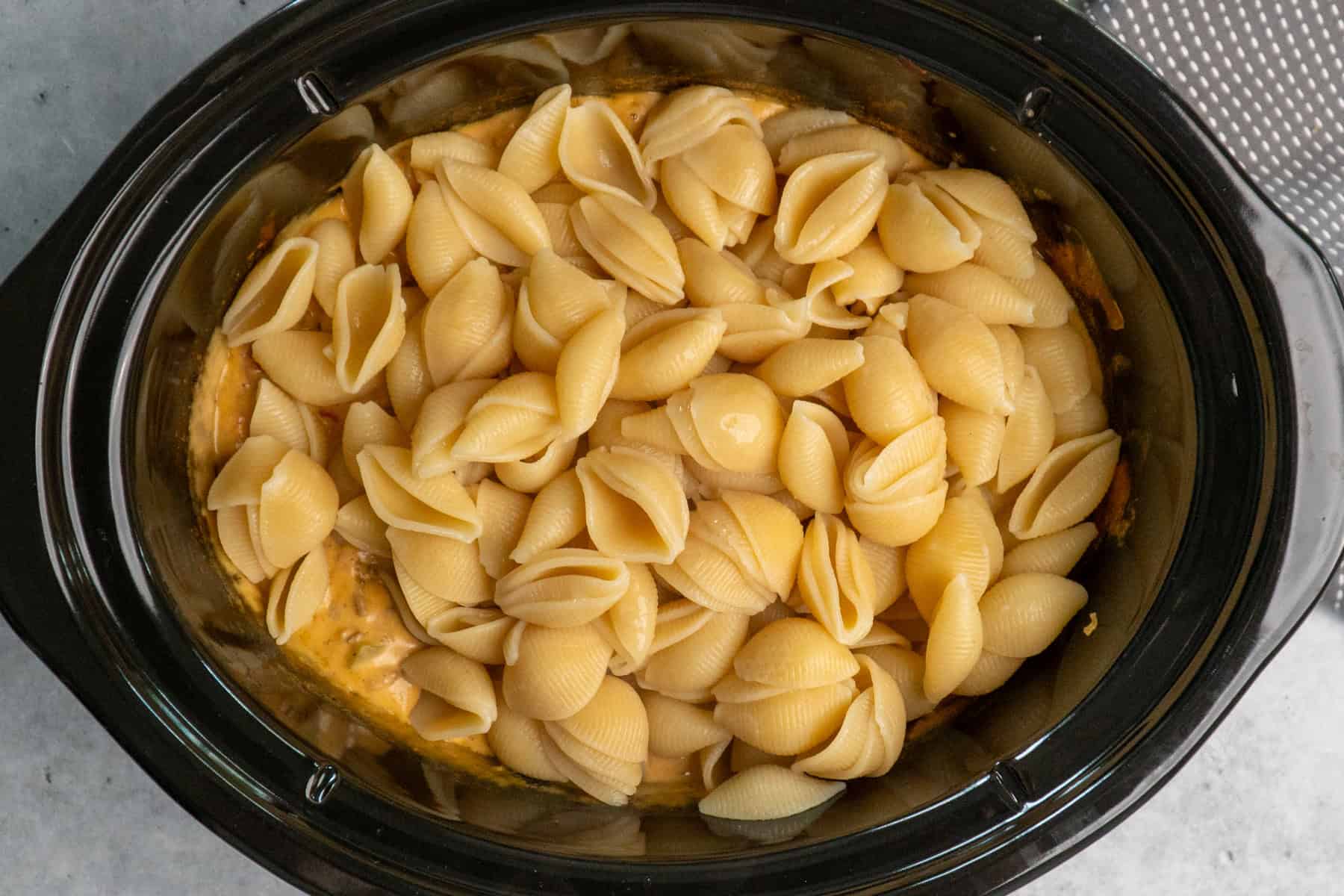 Cooked macaroni shells in a crock pot.