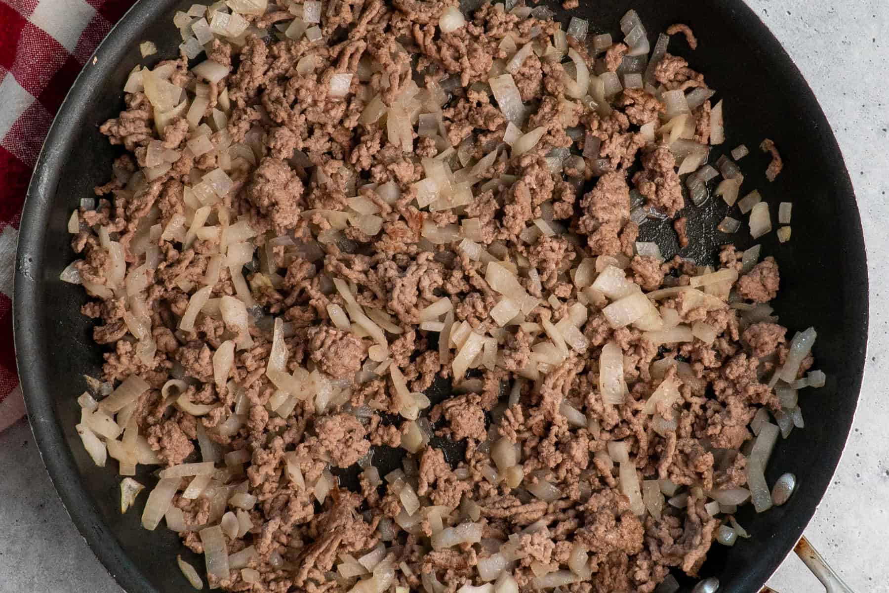 Browned ground beef and onions in a skillet.