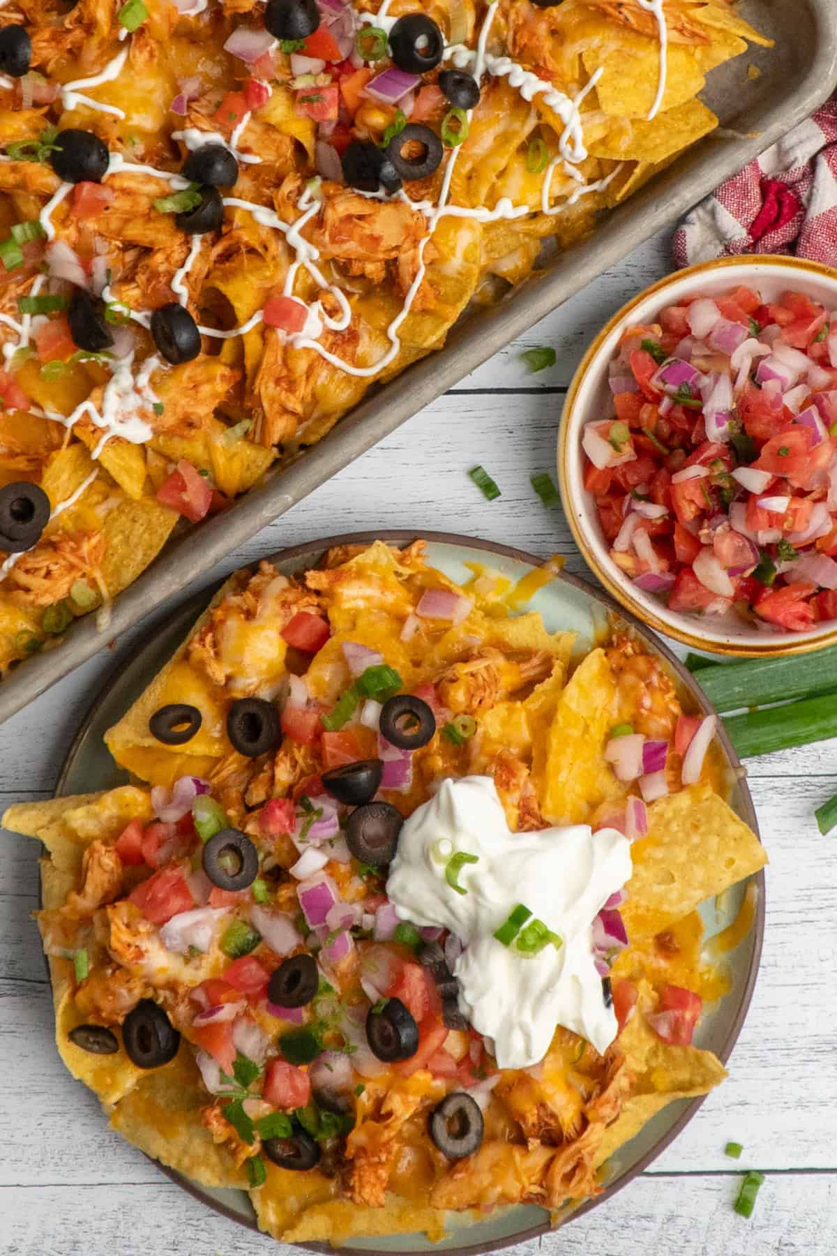 Overhead look at chicken nachos on a baking sheet and on a plate.