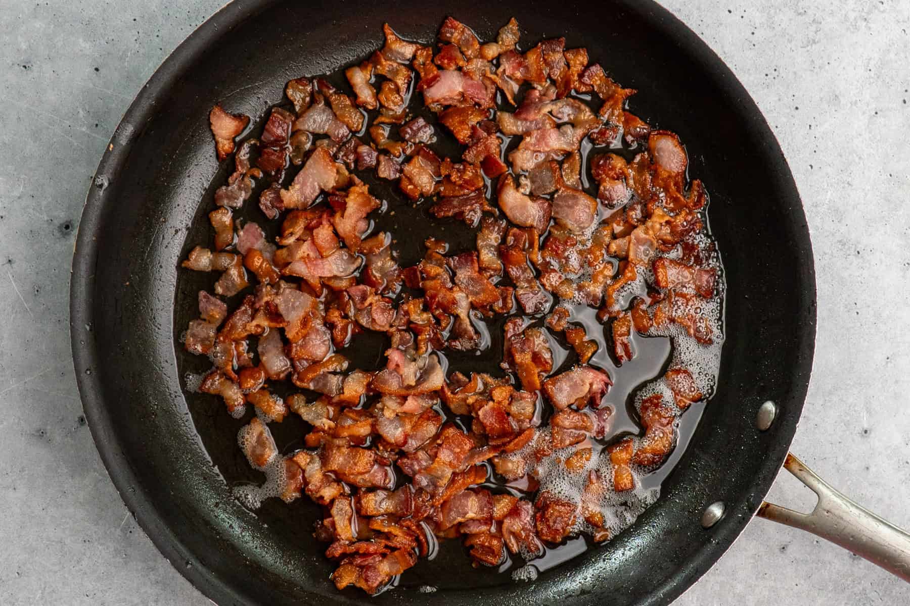 Chopped bacon cooking in a skillet.