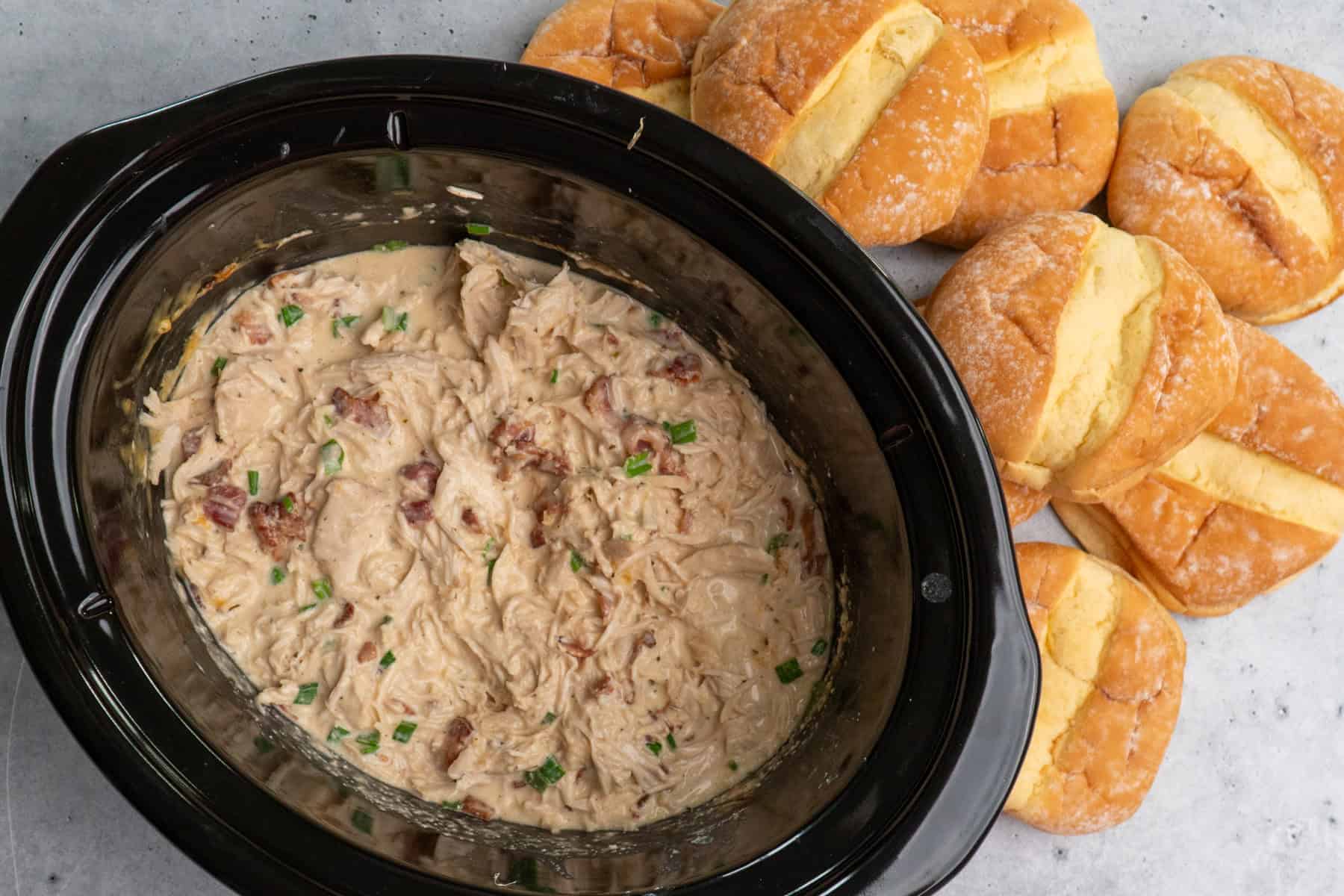 Finished crack chicken in a crock pot ready to be served on buns.