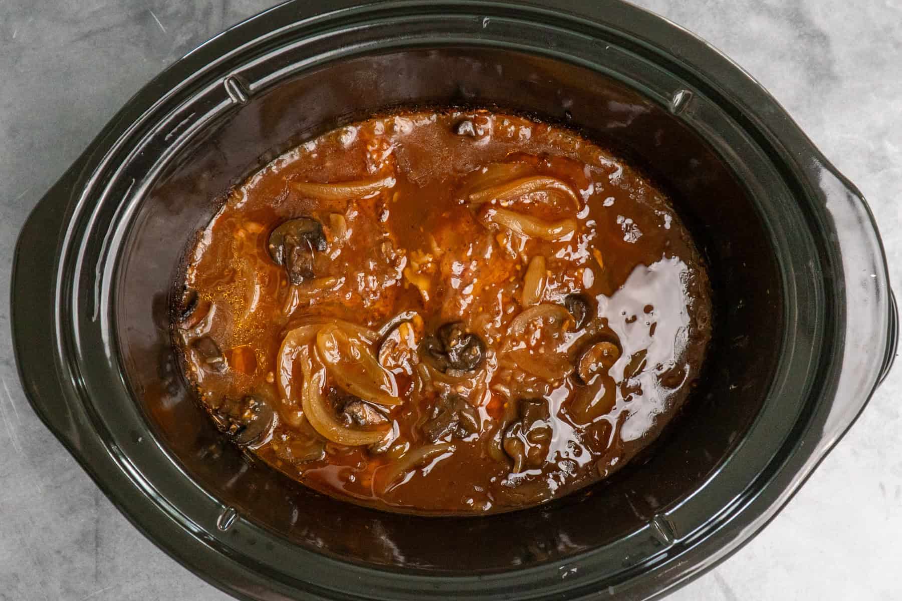 Cooked ribeye steaks in a crock pot ready to be served.