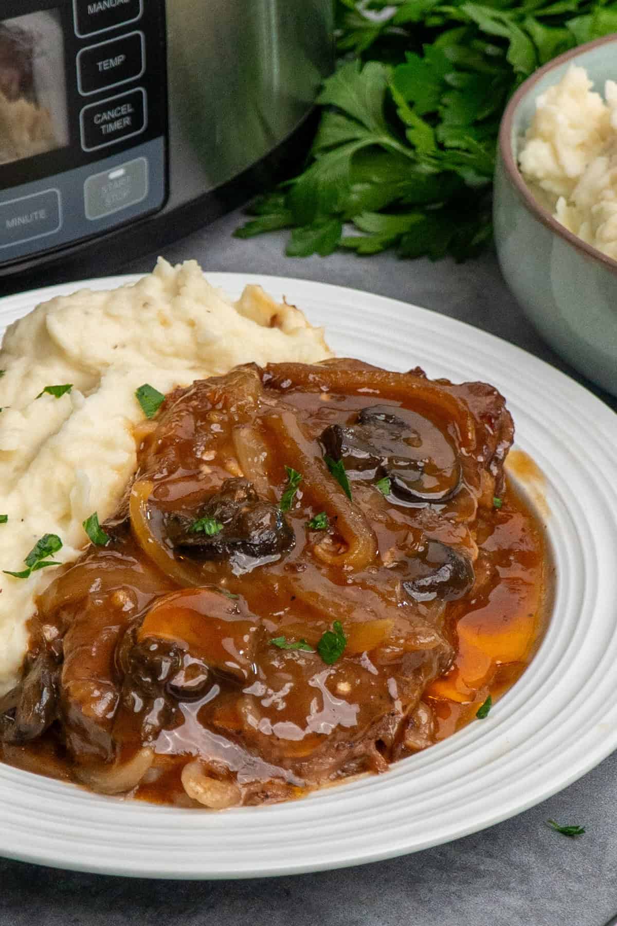 Crock Pot ribeye steak on a plate with mashed potatoes.