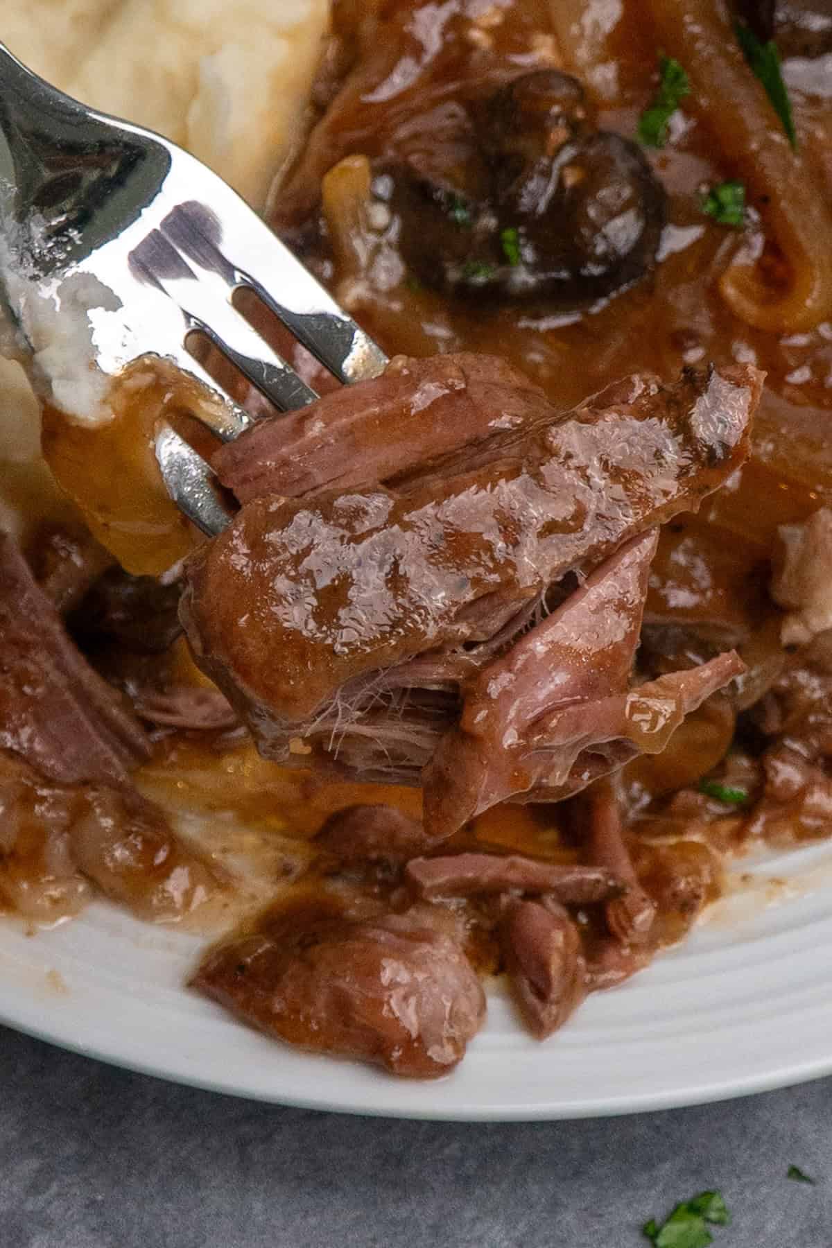 A fork holding a bite of ribeye steak on a fork.