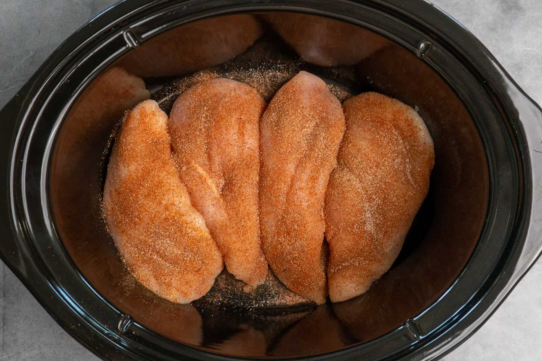 Seasoned chicken breast in a slow cooker.