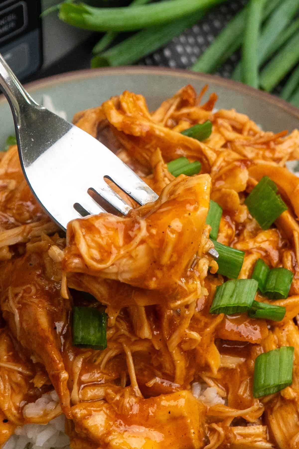 A fork holding a bite of apricot chicken.