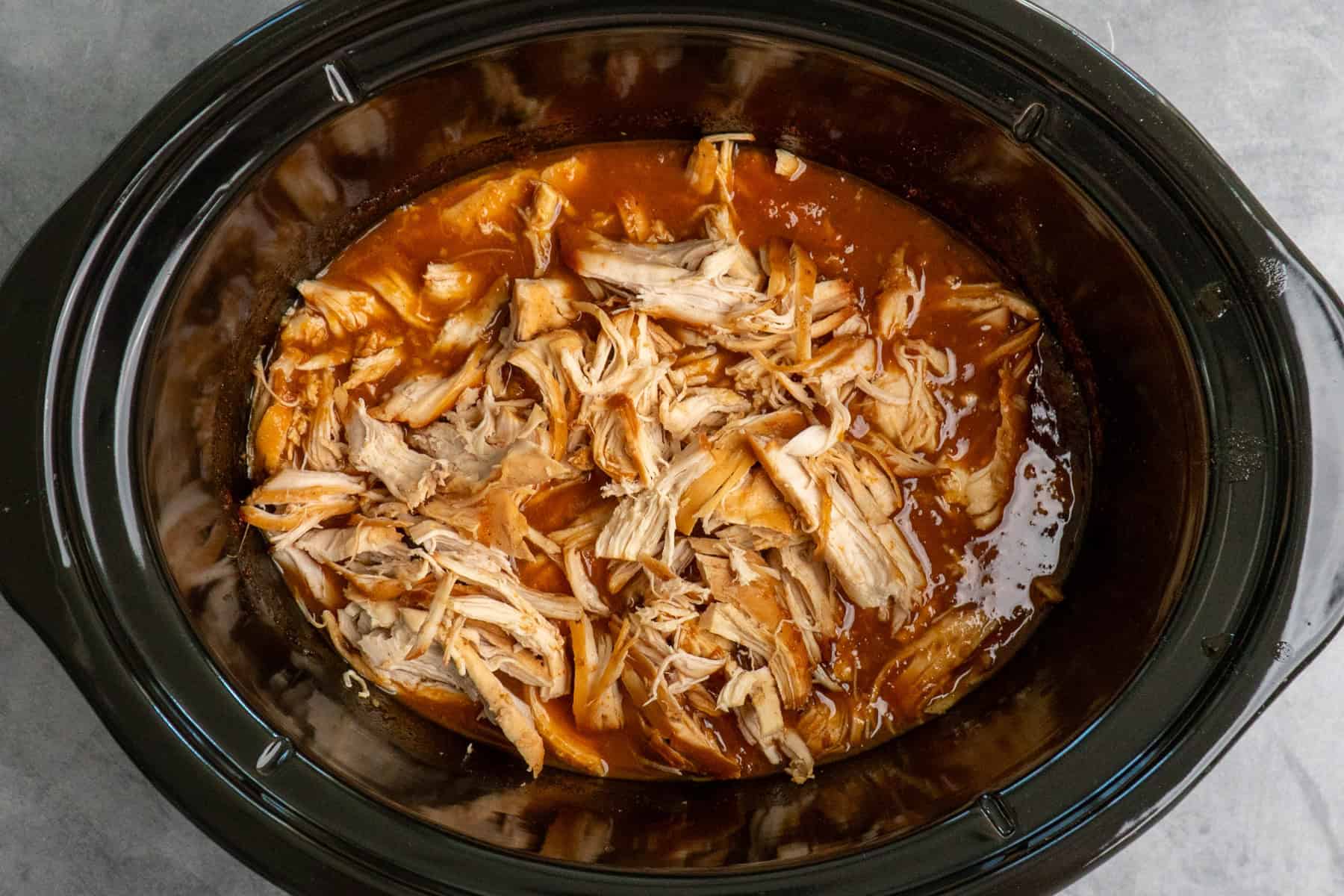 Cooked and shredded chicken in apricot sauce ready to be mixed together.