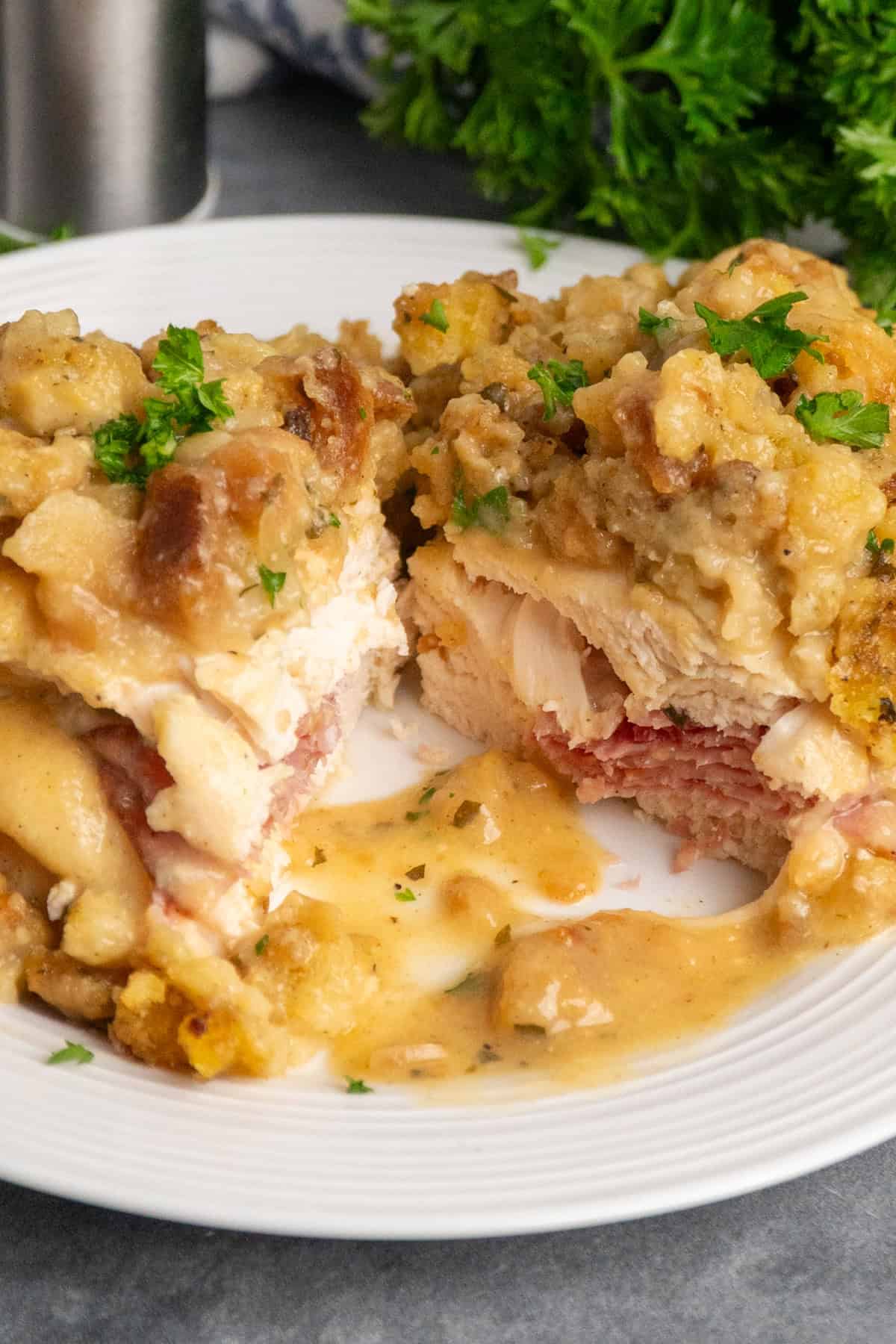 A piece of chicken cordon bleu sliced in half on a white plate.