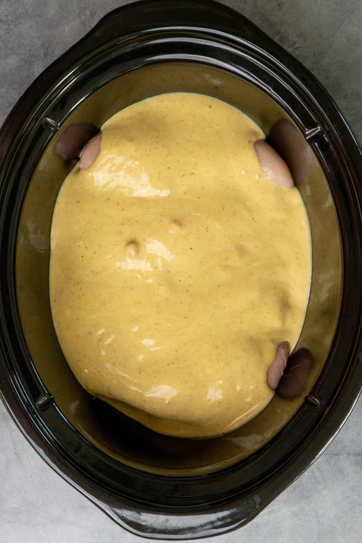 Chicken cordon bleu sauce over chicken in a slow cooker.