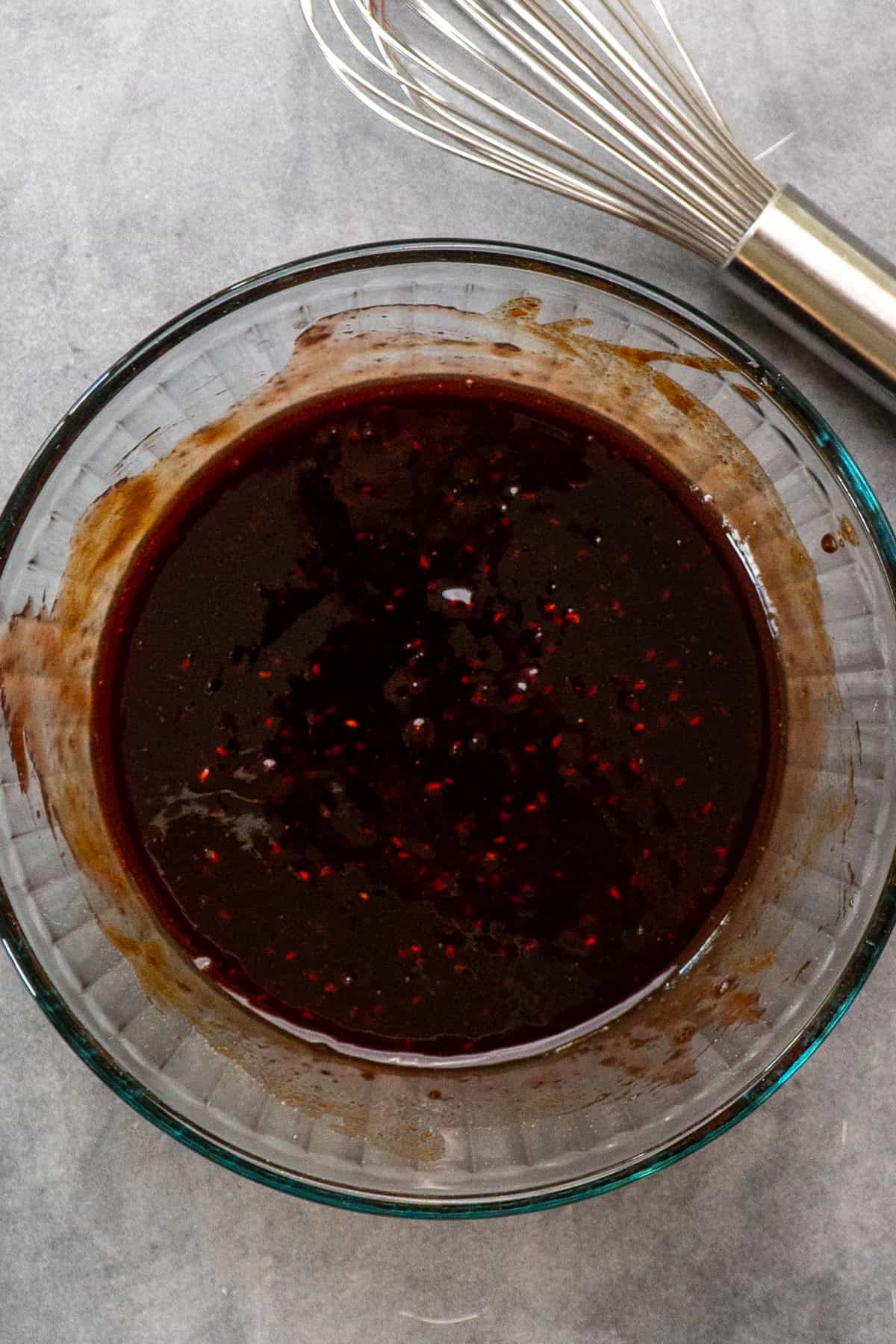 Raspberry sauce for chicken mixed in a bowl with a whisk to the side.