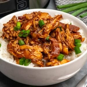 Slow cooker raspberry chicken served up in a bowl on the table over some rice.