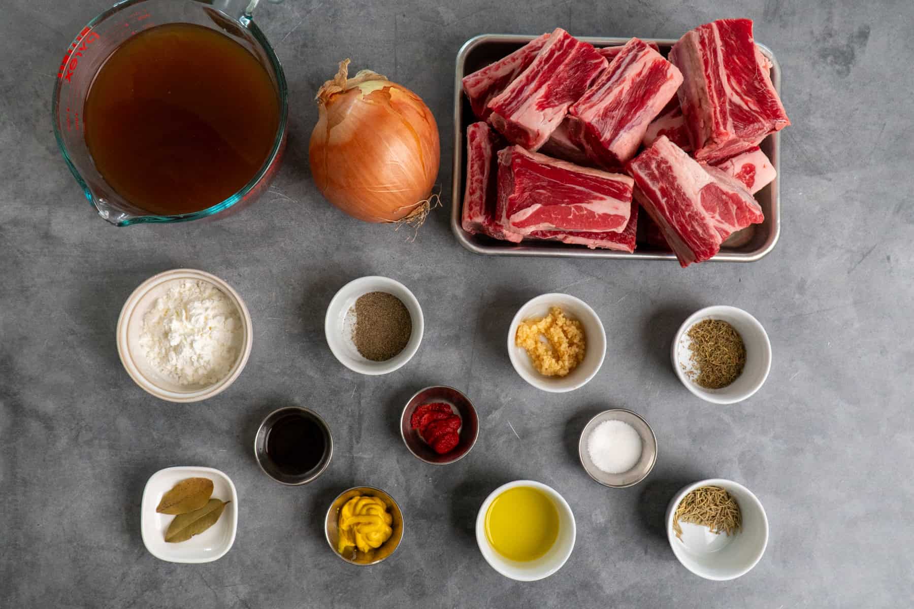 Ingredients to make short ribs on a gray countertop.