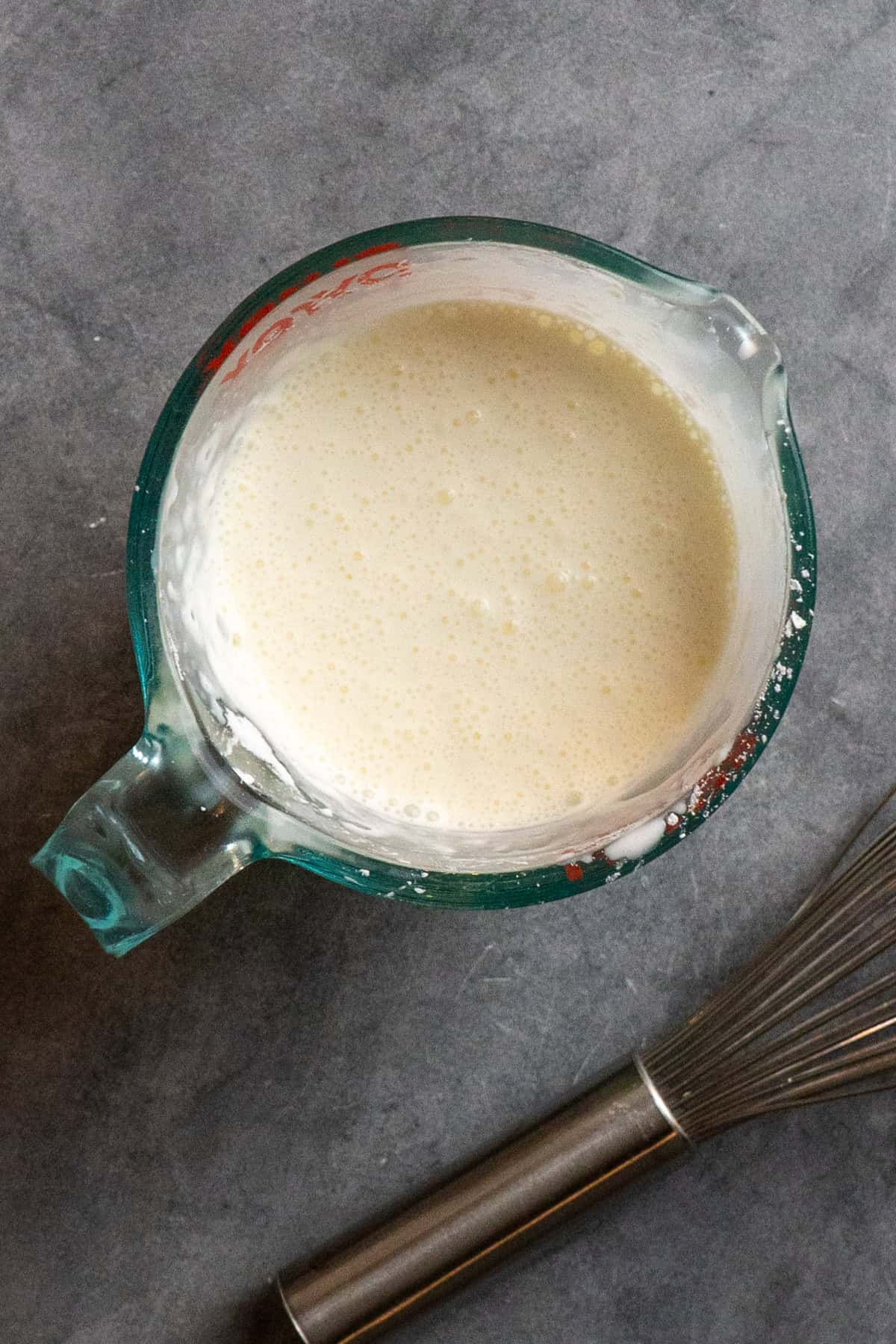 Heavy cream and cornstarch slurry in a glass measuring cup.