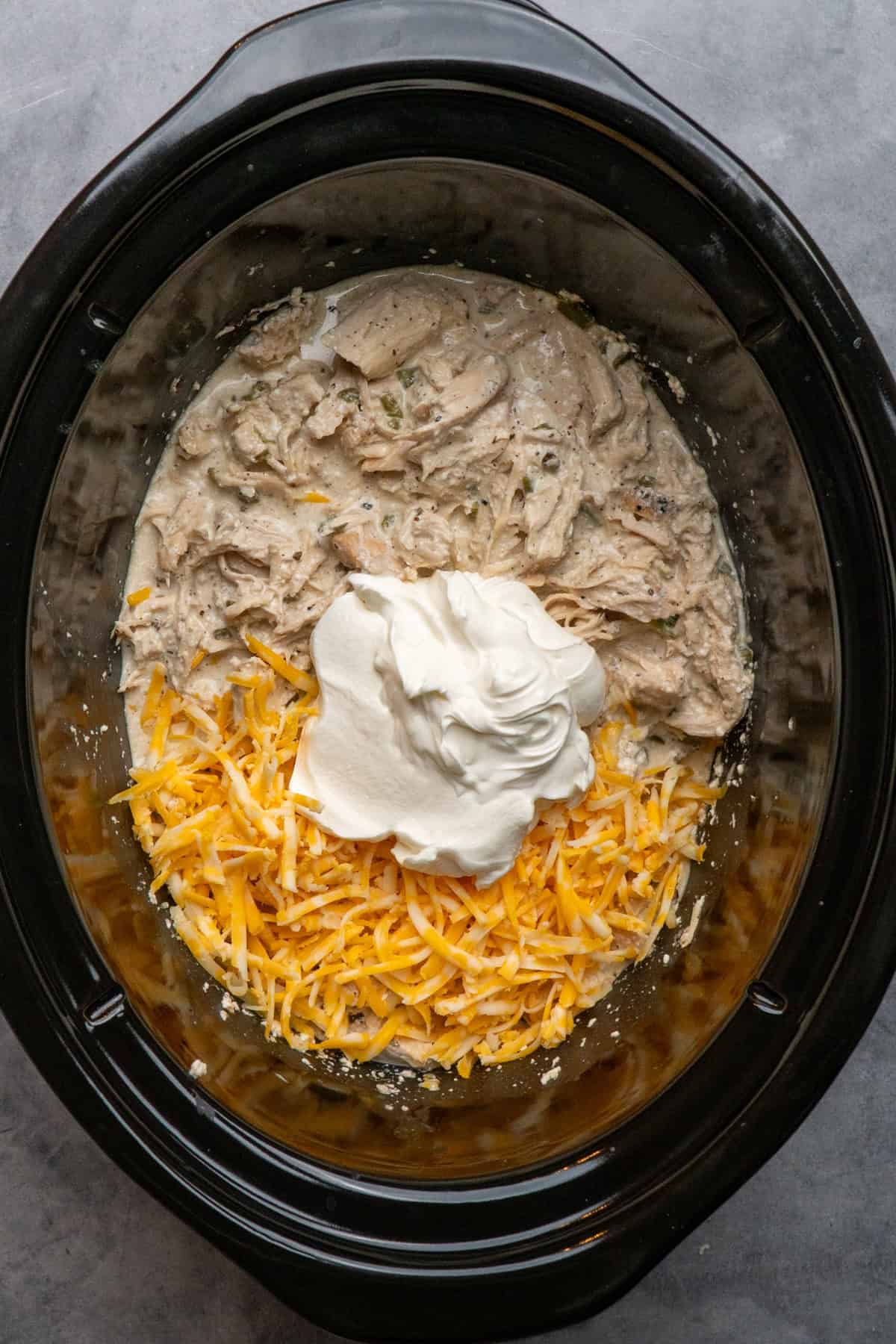 Shredded chicken in a crock pot with cheese and sour cream.