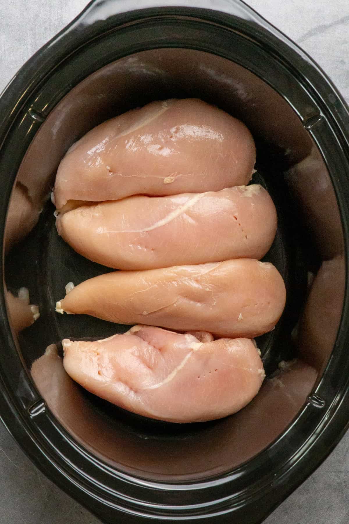 Four chicken breasts in a crock pot.