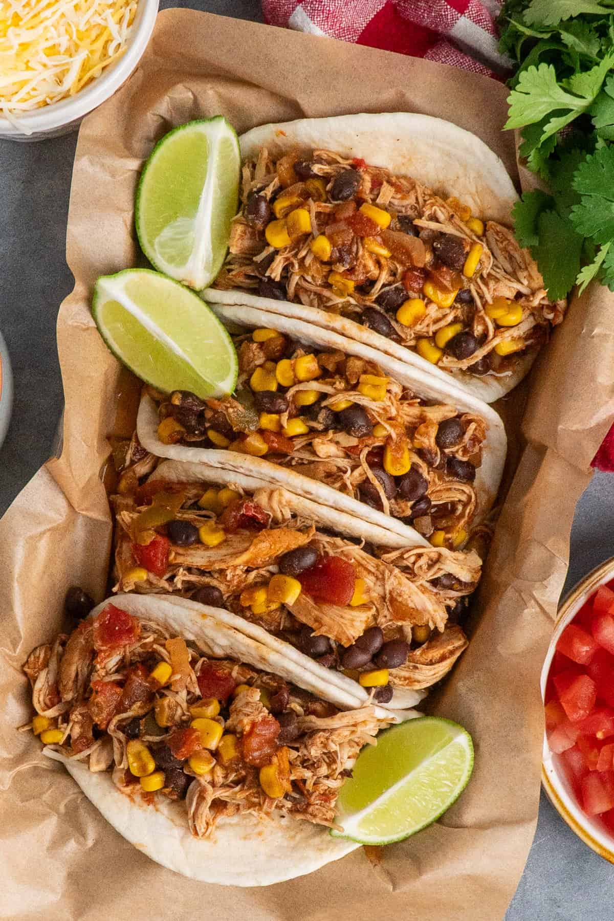 Four southwest chicken taco in a serving tray garnished with limes.