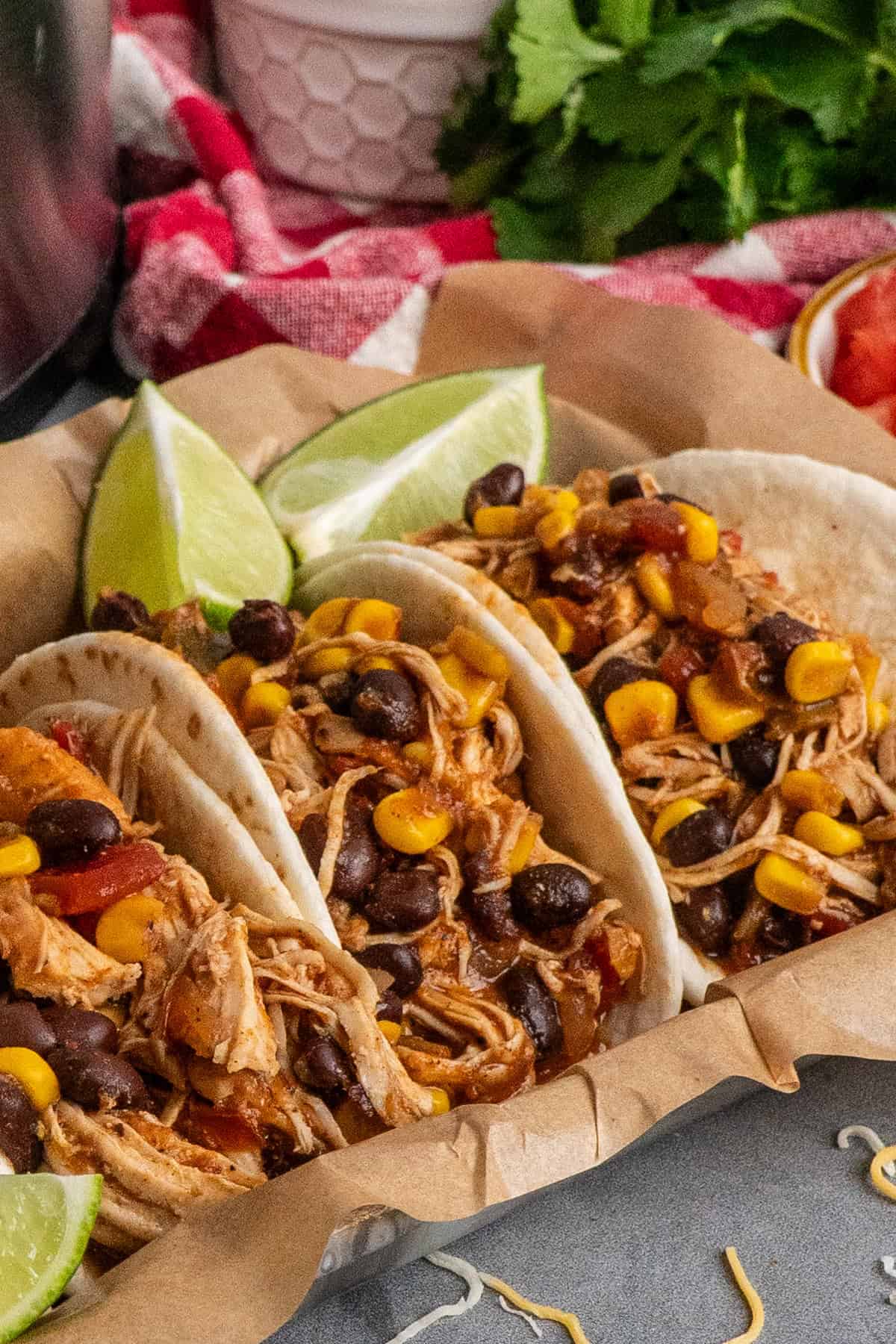 Four crock pot southwest chicken tacos in a tray lined in parchment paper.