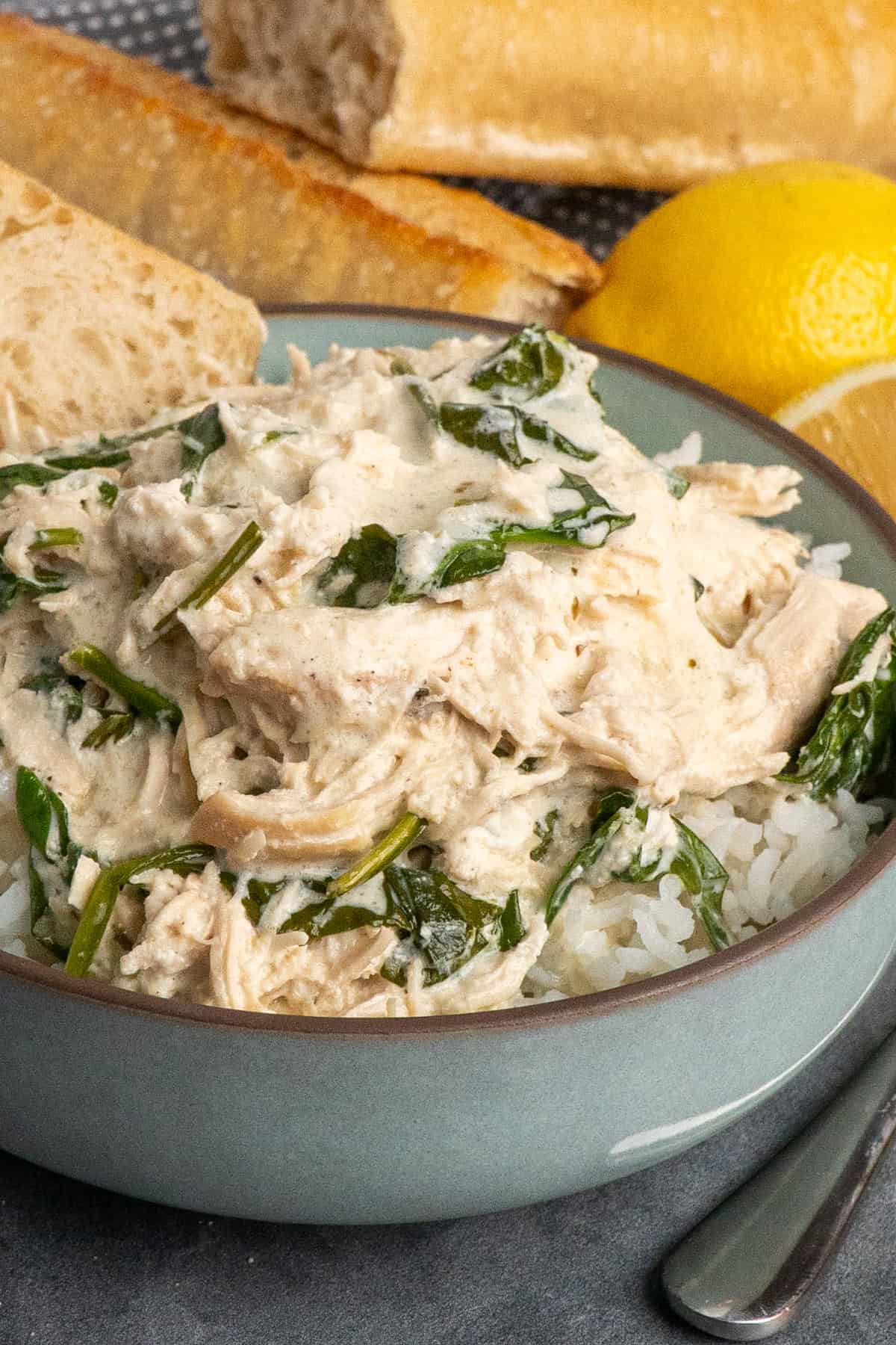 Slow cooker creamy lemon herb chicken over a bowl of rice.