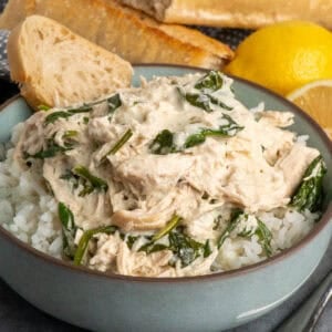 Slow cooker creamy lemon herb chicken over a bowl of rice.