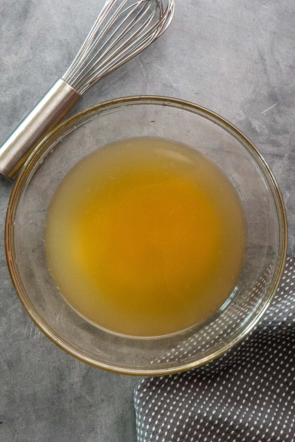 Chicken broth, garlic and lemon juice mixed together in a clear bowl.