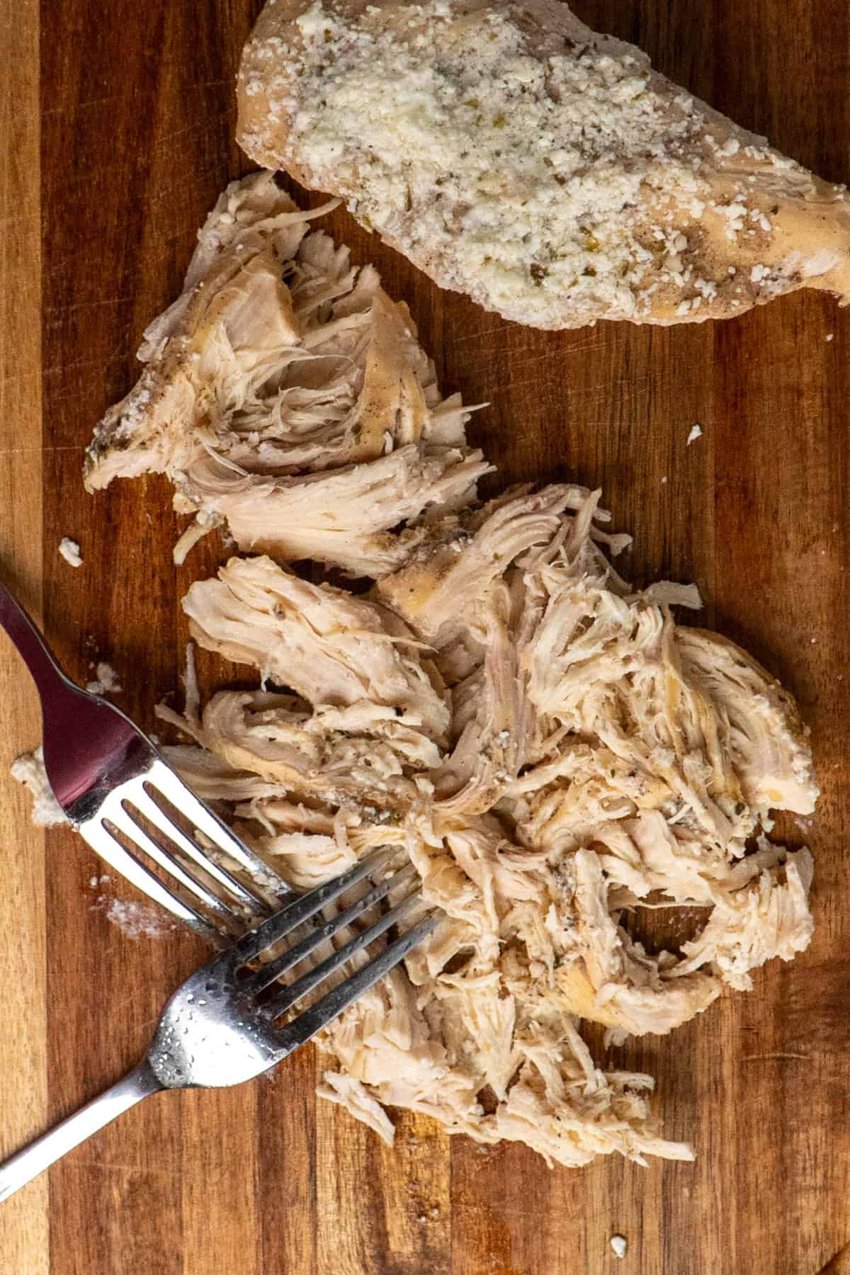 Shredded chicken on a wood cutting board.