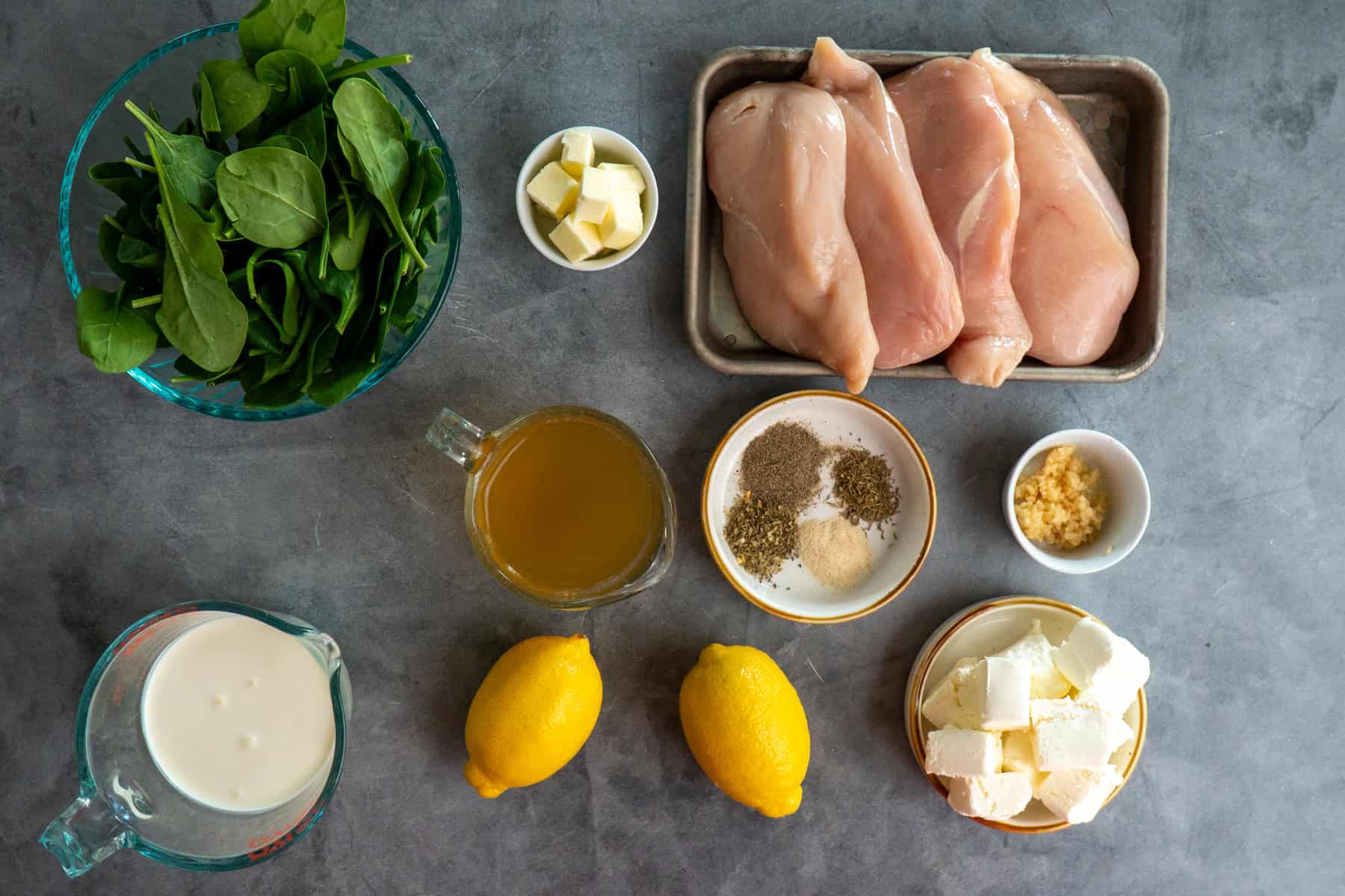 Ingredients to make creamy lemon chicken in a crock pot on a gray countertop.