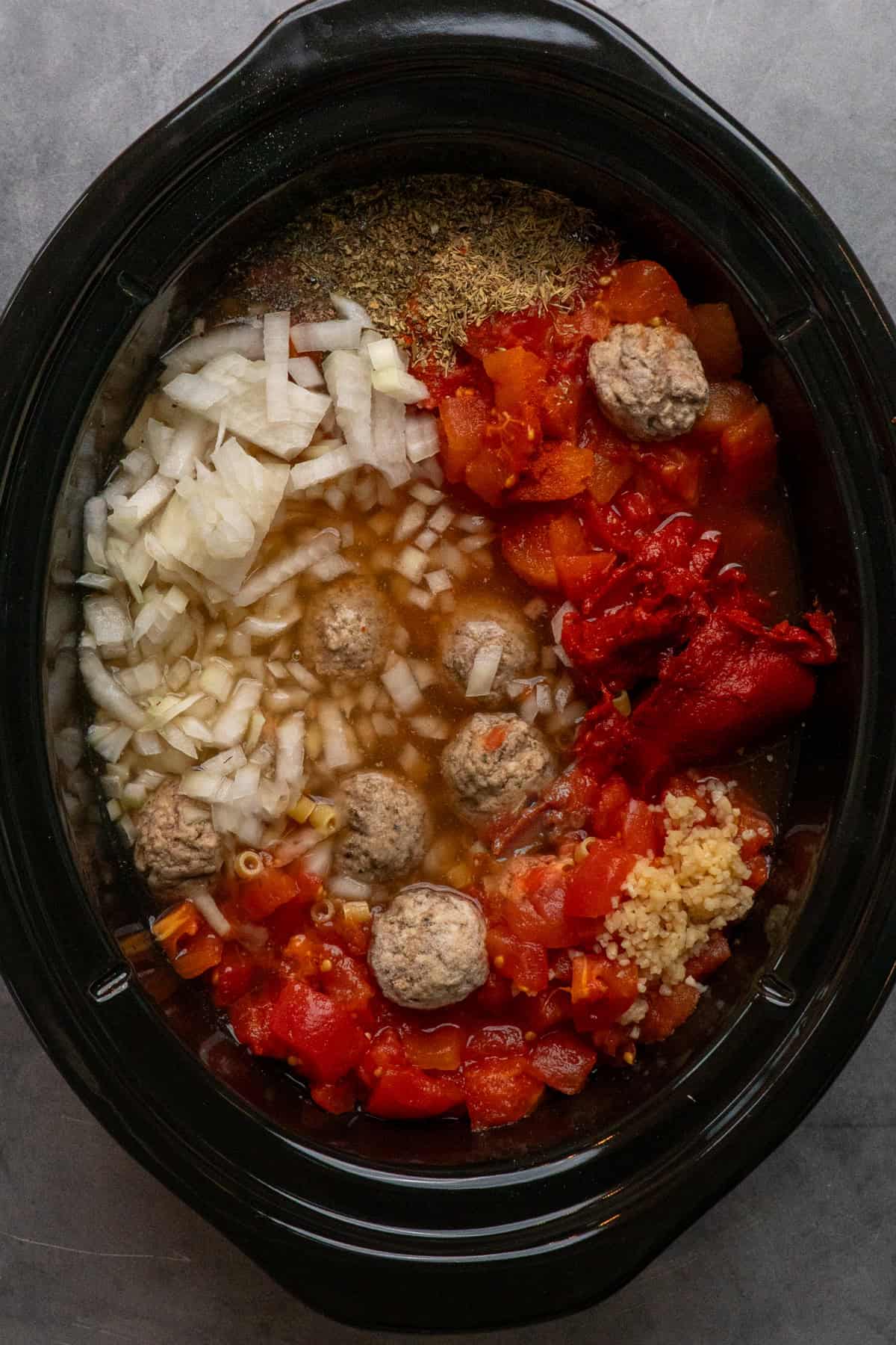 Meatballs, onions, tomatoes, broth and seasonings in a crock pot.