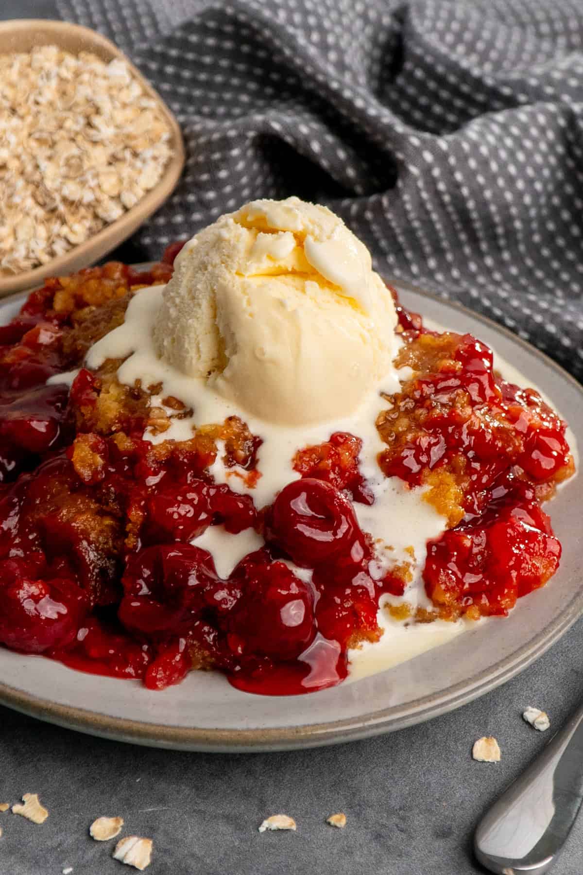 Crock pot cherry cobbler on a plate and topped with vanilla ice cream.