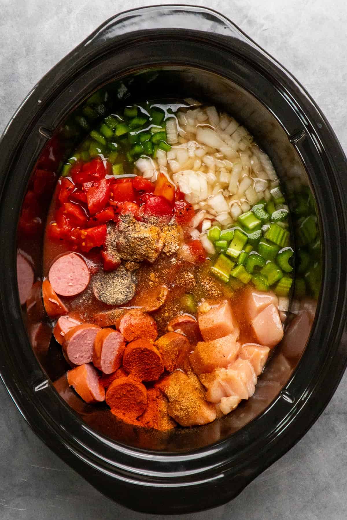 Chicken and sausage gumbo ingredients in a slow cooker.