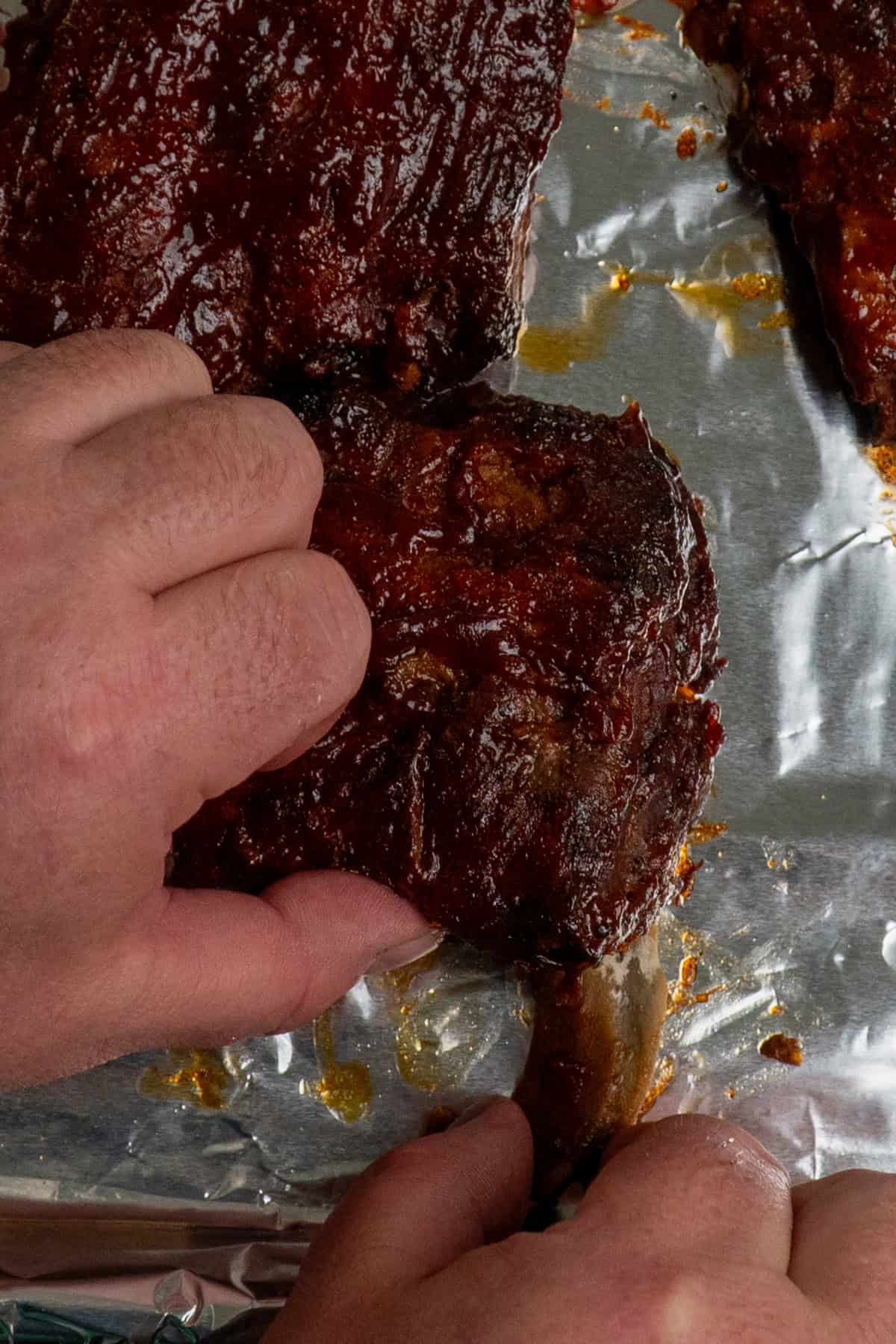 A hand removing a bone from the ribs.