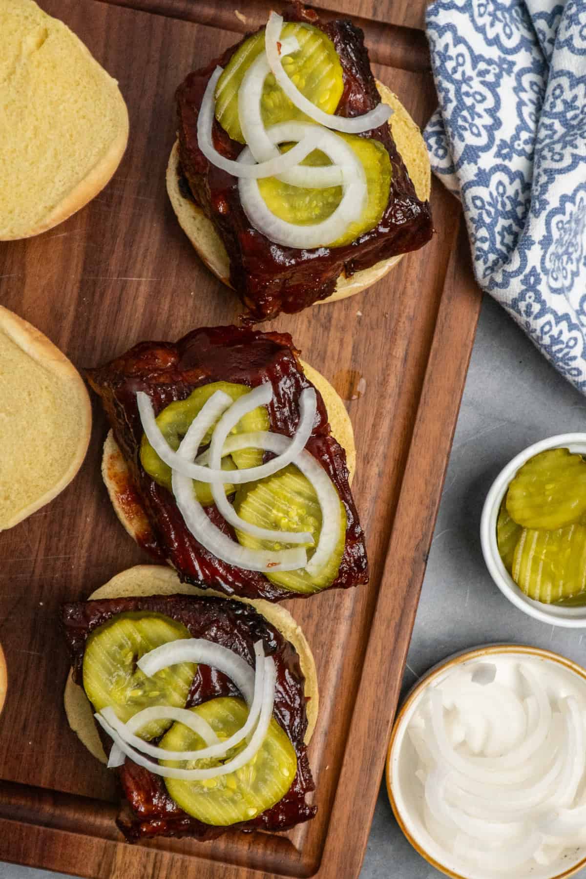 Buns topped with boneless rib meat topped with pickles and onions.