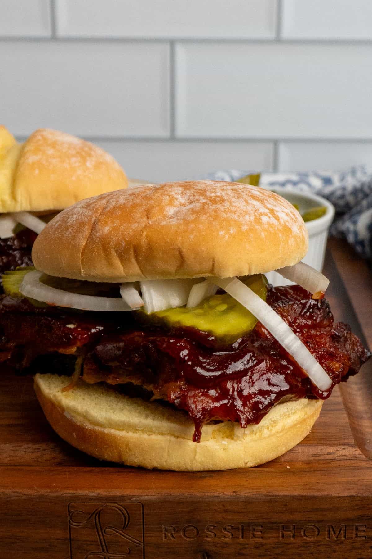 A boneless bbq rib sandwich with pickles and onions.