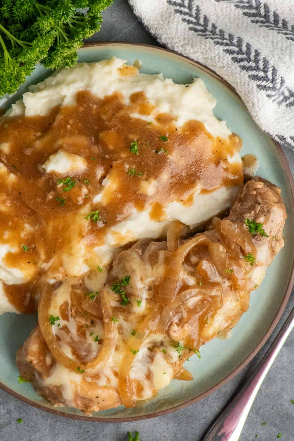 A French onion pork chop on a plate with mashed potatoes.