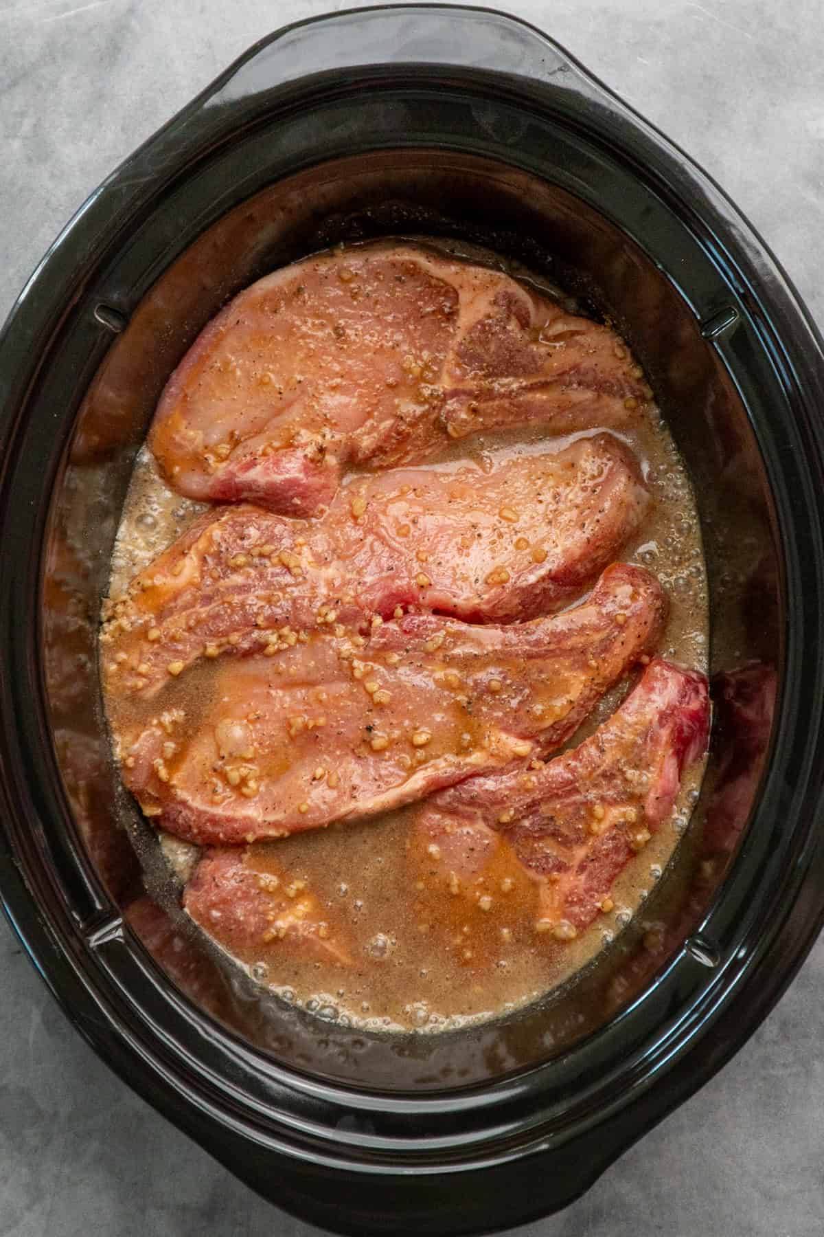 French onion sauce poured over pork chops in a crock pot.