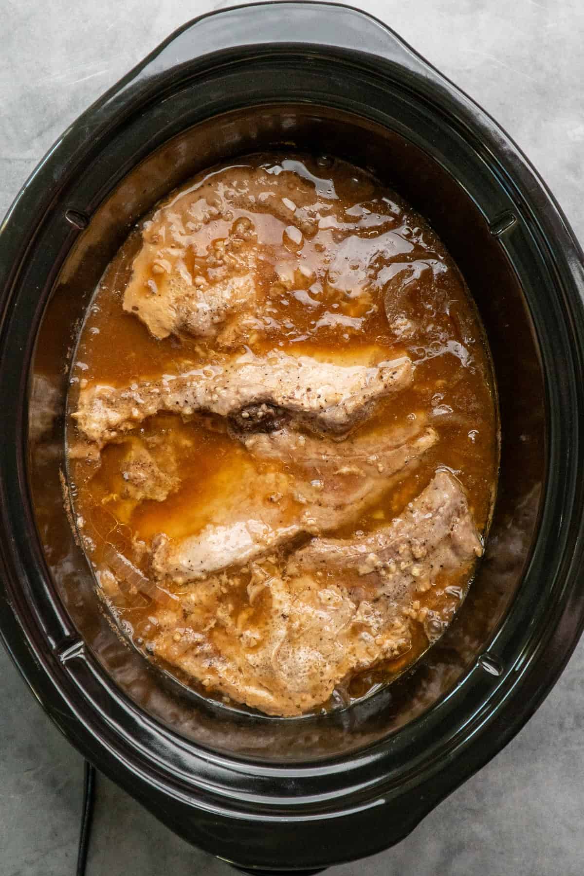 Cooked pork chops ready to be removed from the crock pot.