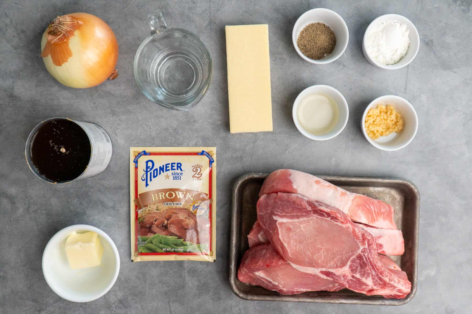 Ingredients to make French onion pork chops in a crock pot on a granite countertop.