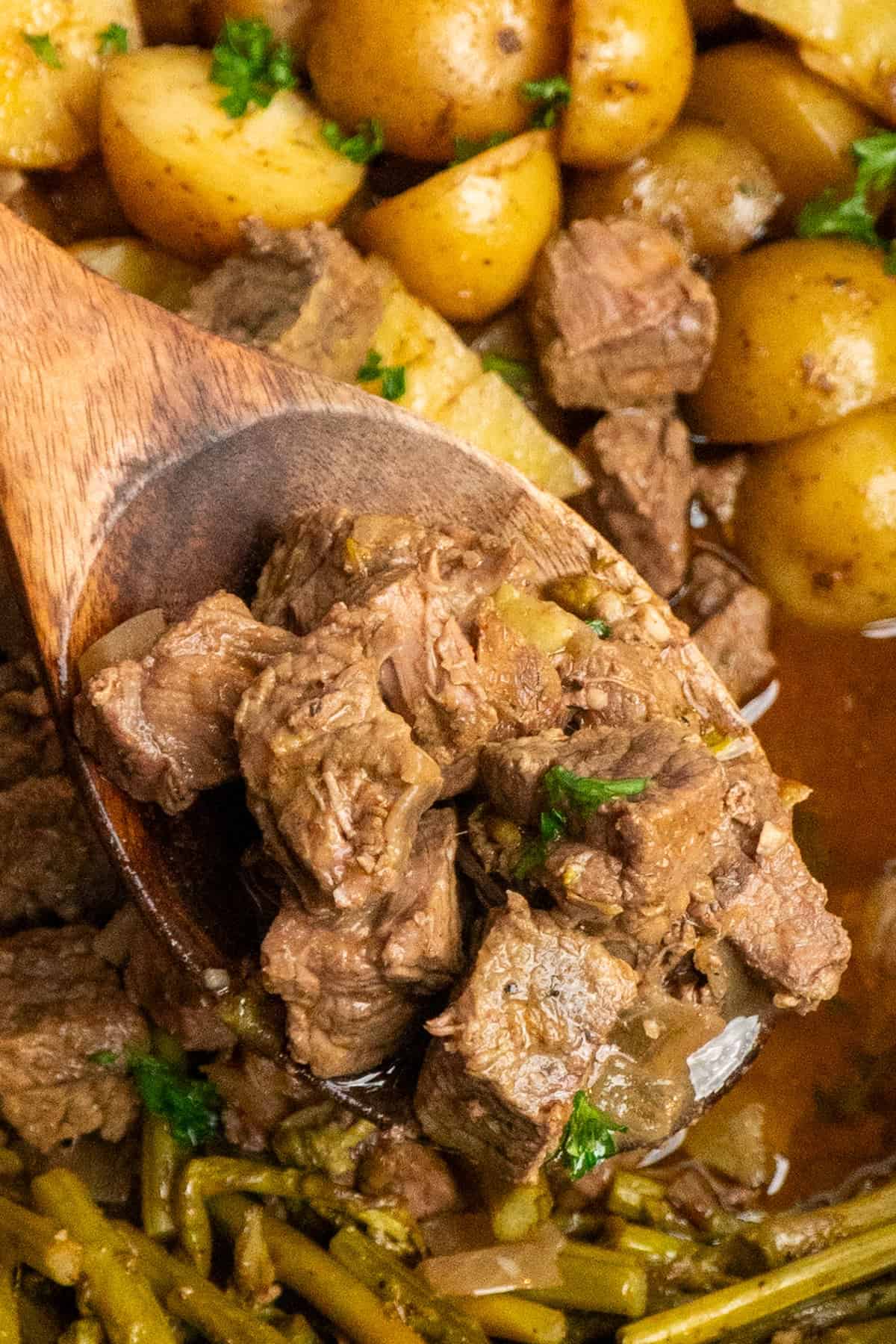 A wooden spoon holding a serving of garlic butter steak bites.