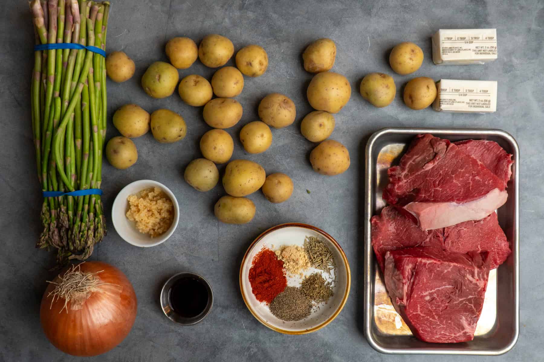 Ingredients to make garlic butter steak bites on a gray marble countertop.