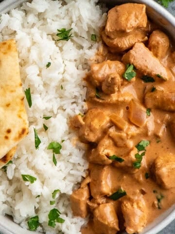 Crock Pot tikka masala in a bowl with rice and naan bread.