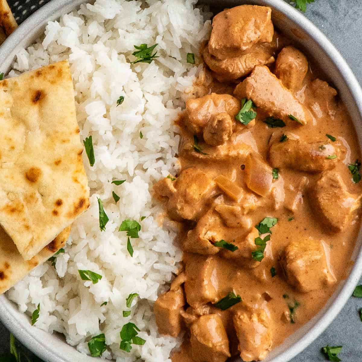 Crock Pot tikka masala in a bowl with rice and naan bread.