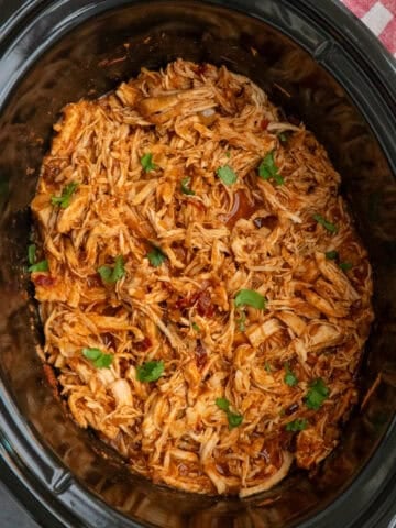 Mexican chicken that has been shredded in a slow cooker and ready to serve.