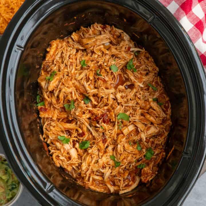 Mexican chicken that has been shredded in a slow cooker and ready to serve.