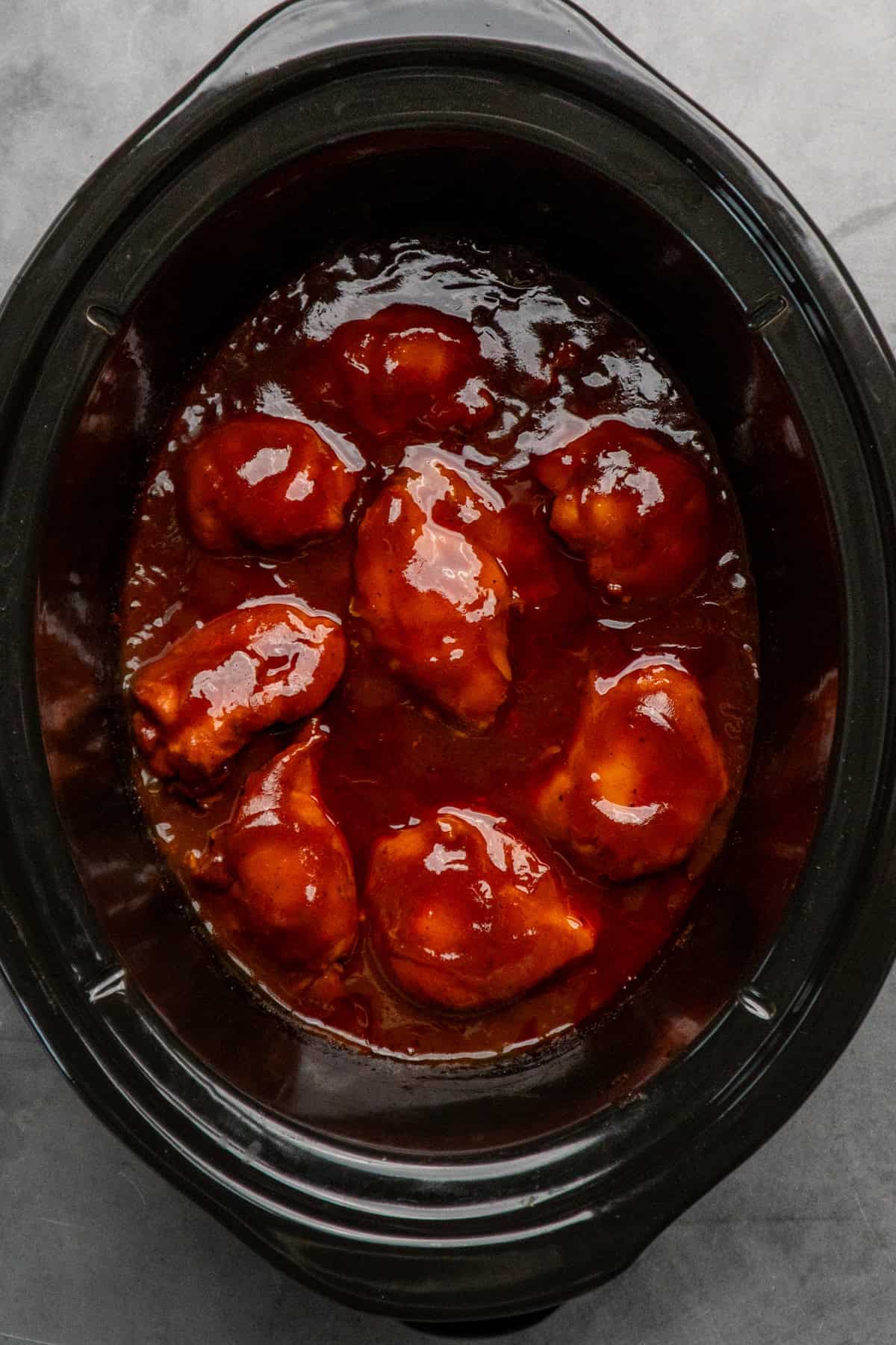 Cooked chicken thighs in BBQ sauce.