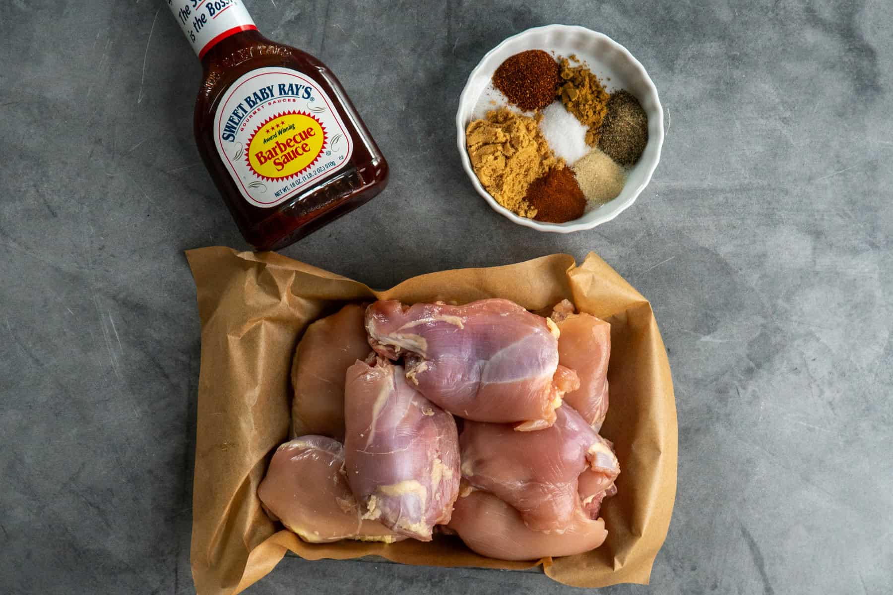 Ingredients for BBQ chicken thighs on a gray countertop.